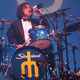 jason finn wearing a suit and drinking a beer on the drums